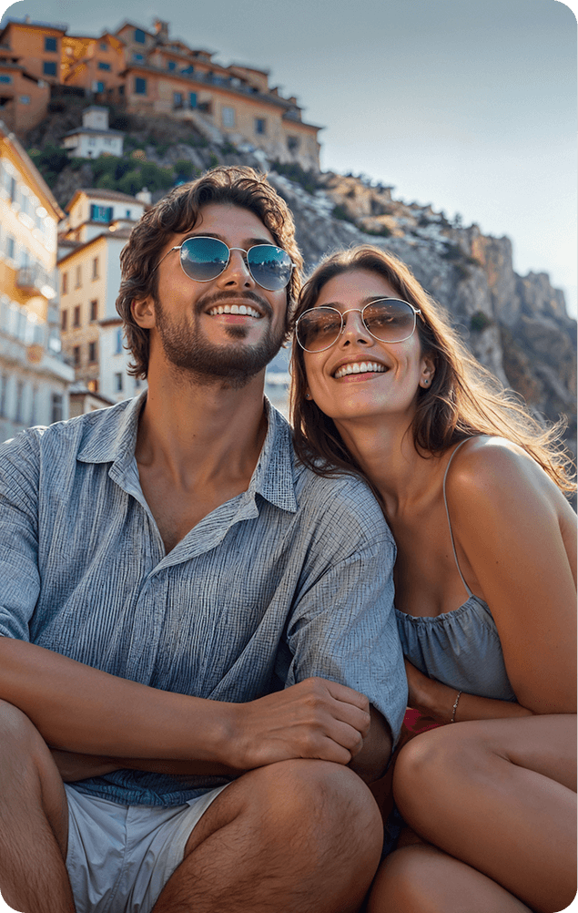 Pareja de jóvenes sentados sonriendo con un pueblo de fondo
