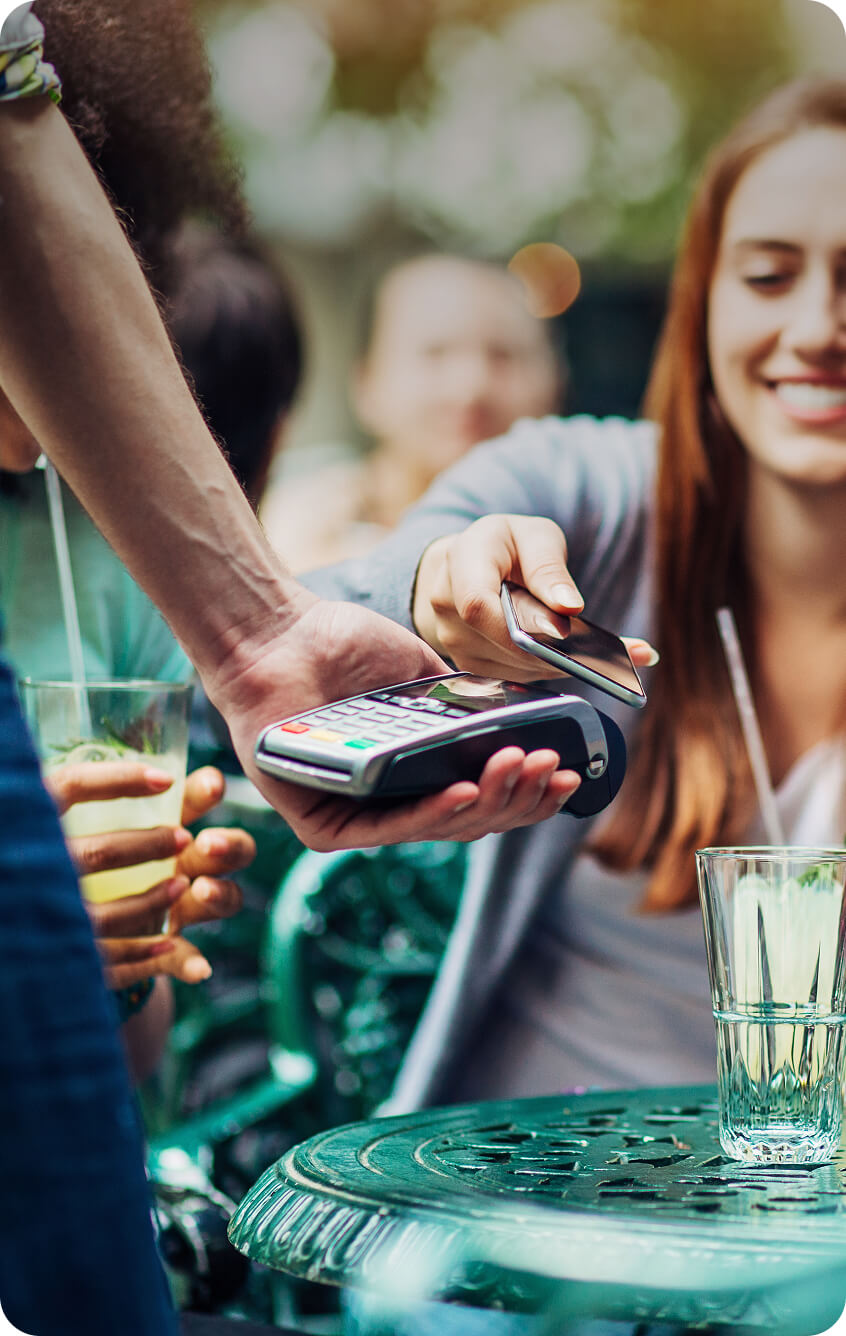 Mujer joven pagando con una tarjeta en una cafetería