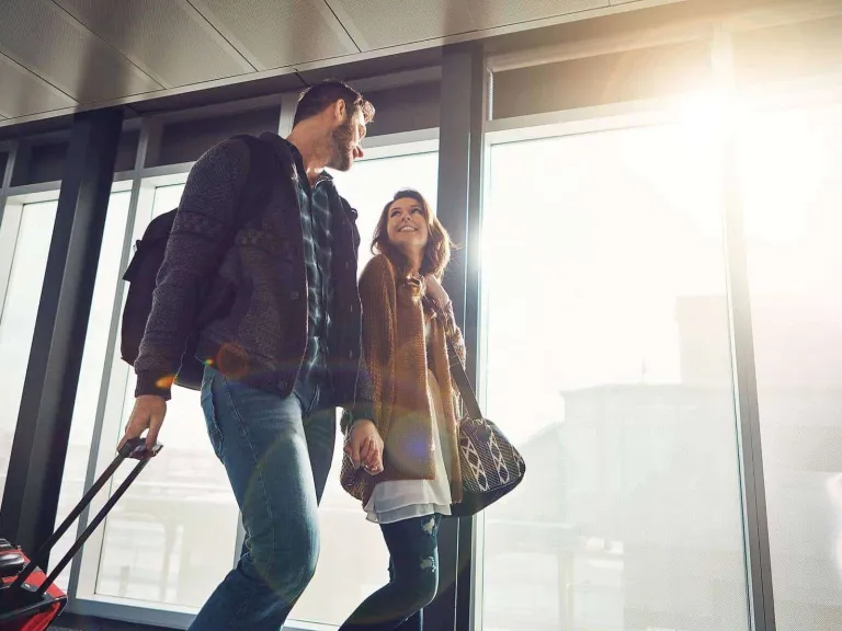 Diners Club Aadvantage asistencia médica: Un hombre y una mujer caminando con sus maletas de viaje