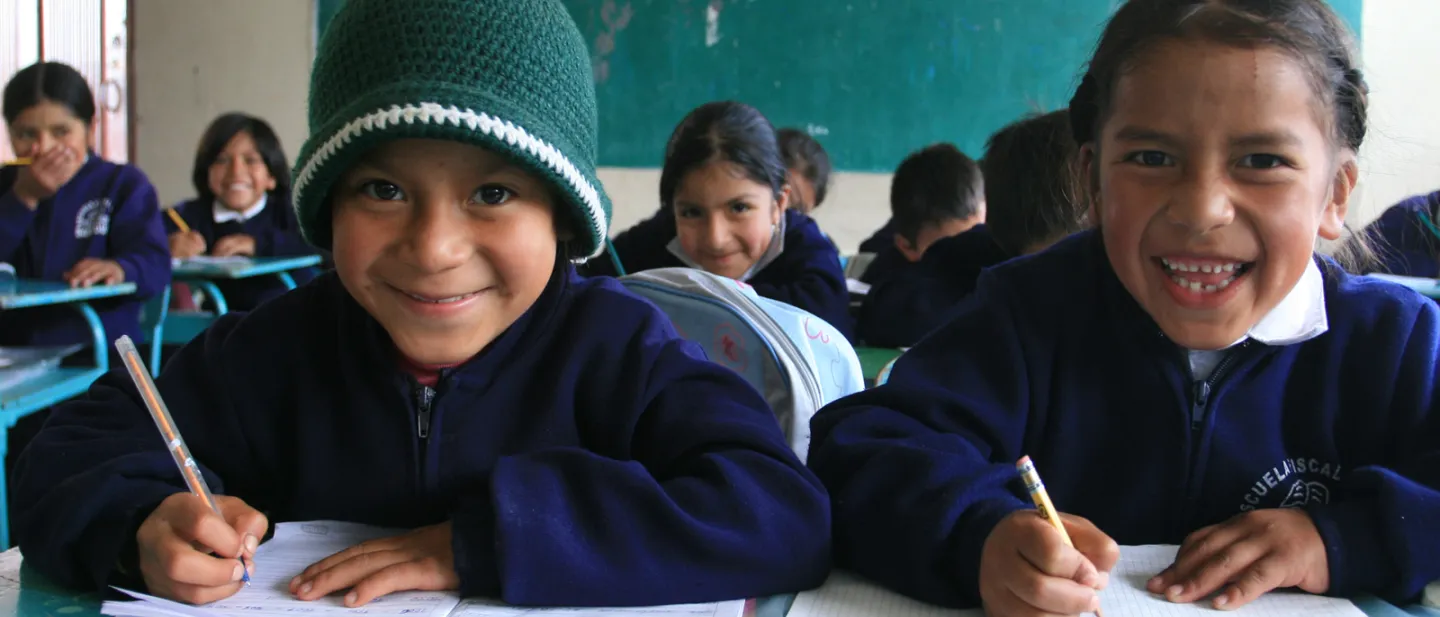 Niños en el salón de clases sentados en sus pupitres 
