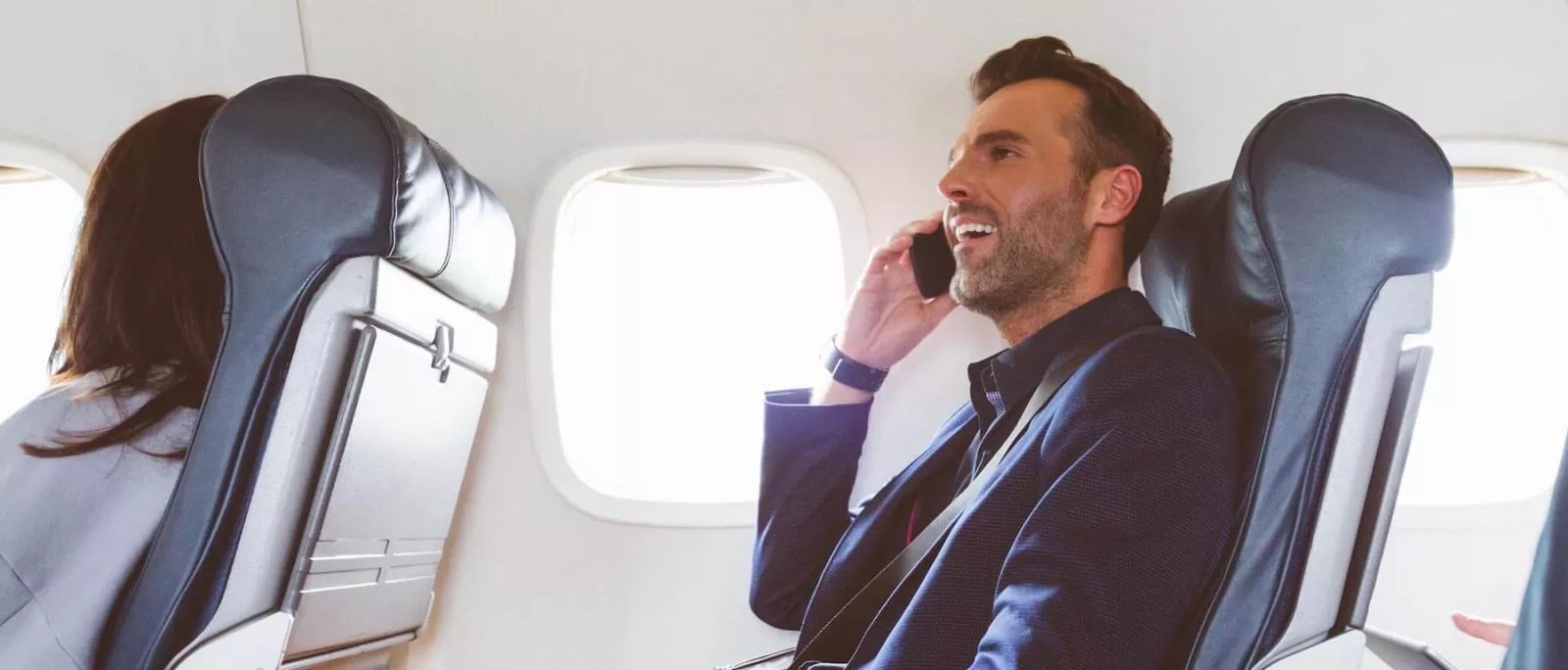 Hombre sentado en un avión hablando por teléfono