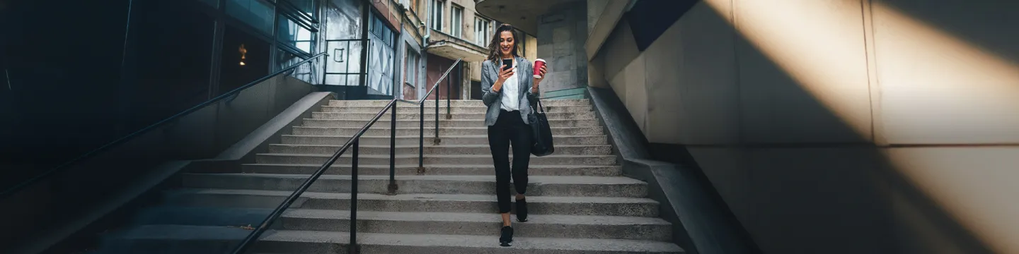 Mujer joven bajando escaleras y mirando el móvil